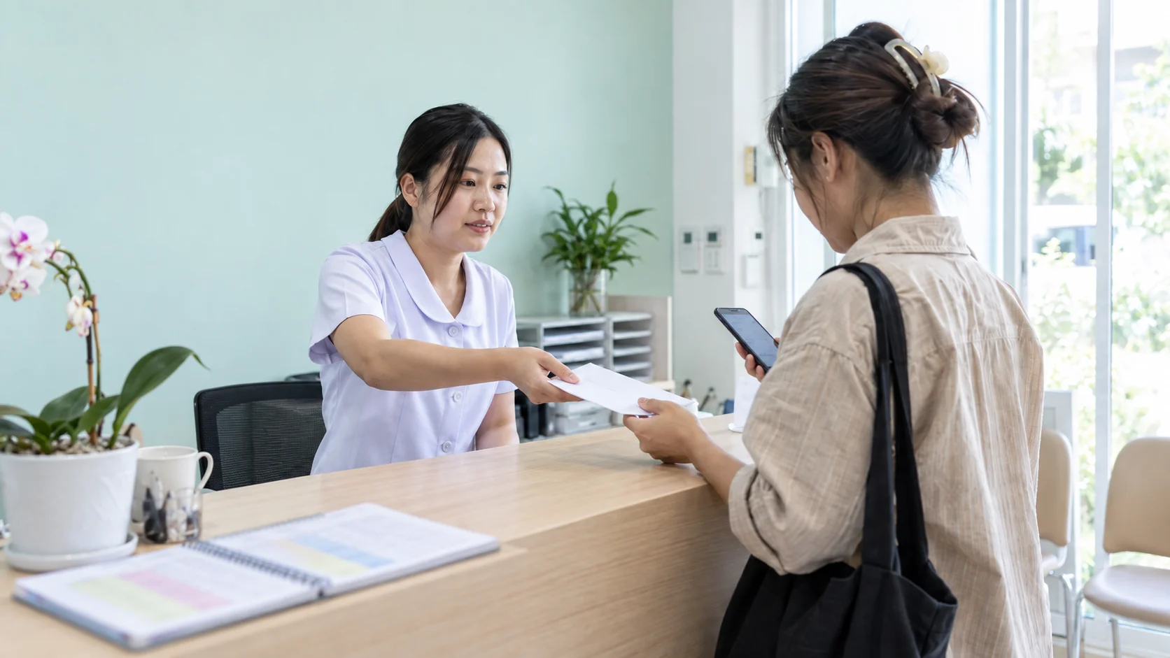 พนักงานคลินิกยื่นบัตรของขวัญคลินิกให้ลูกค้าที่เคาน์เตอร์